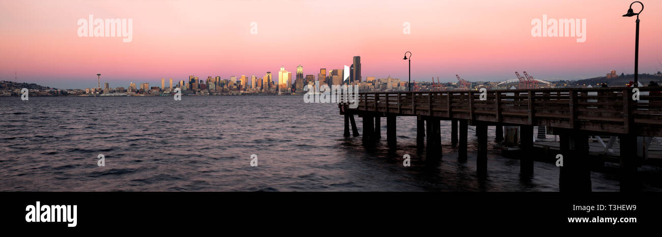 WA16107-00...WASHINGTON - die untergehende Sonne sorgt bei Sonnenuntergang im Seacrest Park an den Ufern der Elliott Bay, 2018, für ein Leuchten auf den Hochhäusern in Seattle. Stockfoto