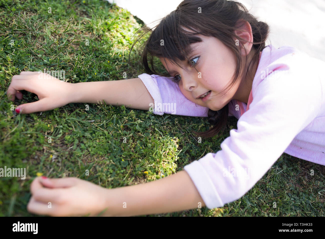6-7 Jahre alten Mädchen mit auf dem Gras und Ausflüge in die Natur. Stockfoto