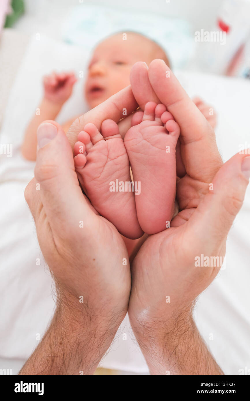 Füße eines neugeborenen Jungen in die Arme seines Vaters gewickelt Stockfoto