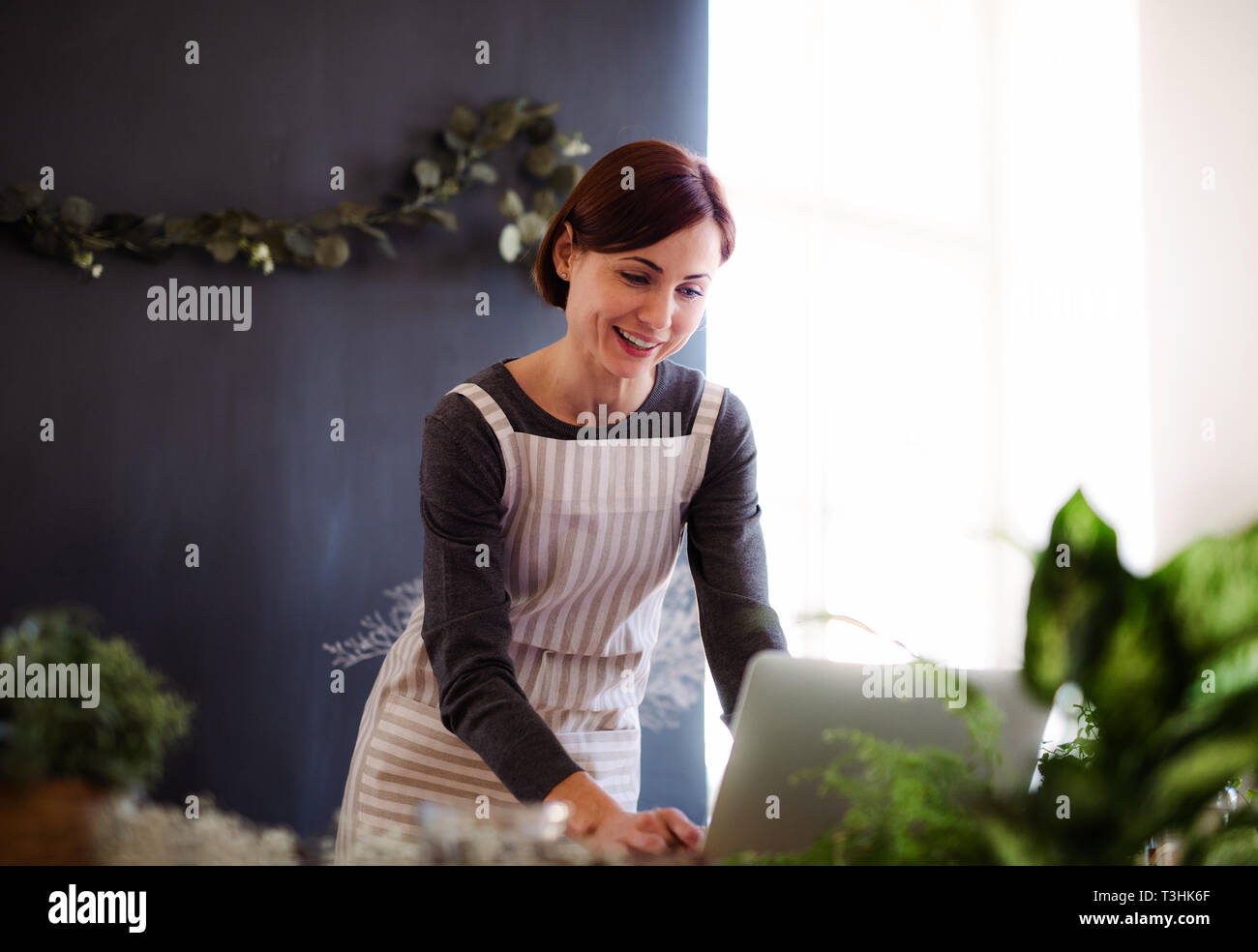 Junge kreative Frau in einem Blumenladen, mit Laptop. Ein Anlauf von Blumengeschäft Geschäft. Stockfoto