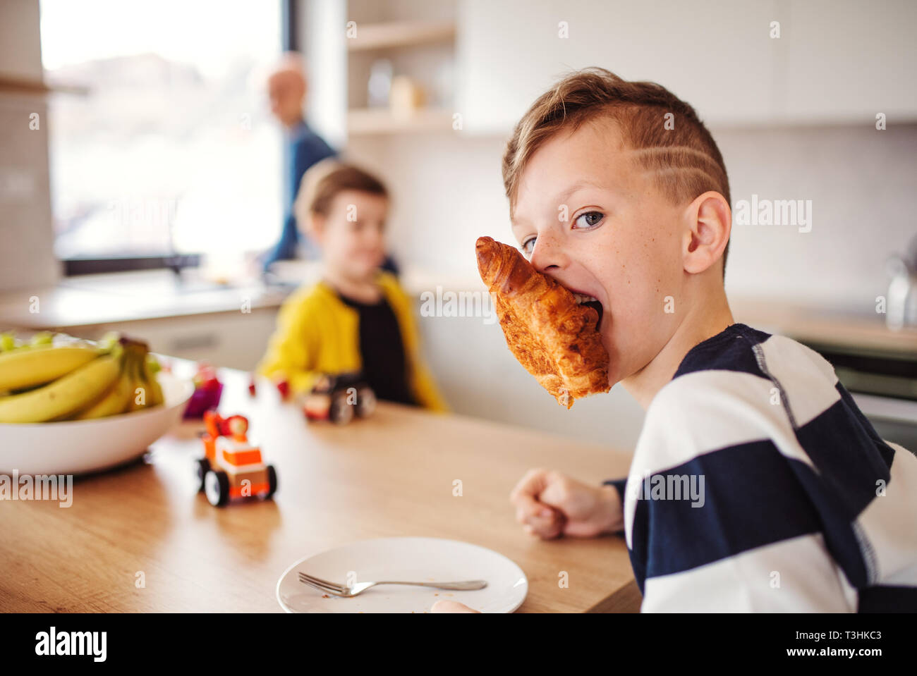 Zwei kleine Kinder mit Mutter in einer Küche, Essen. Stockfoto