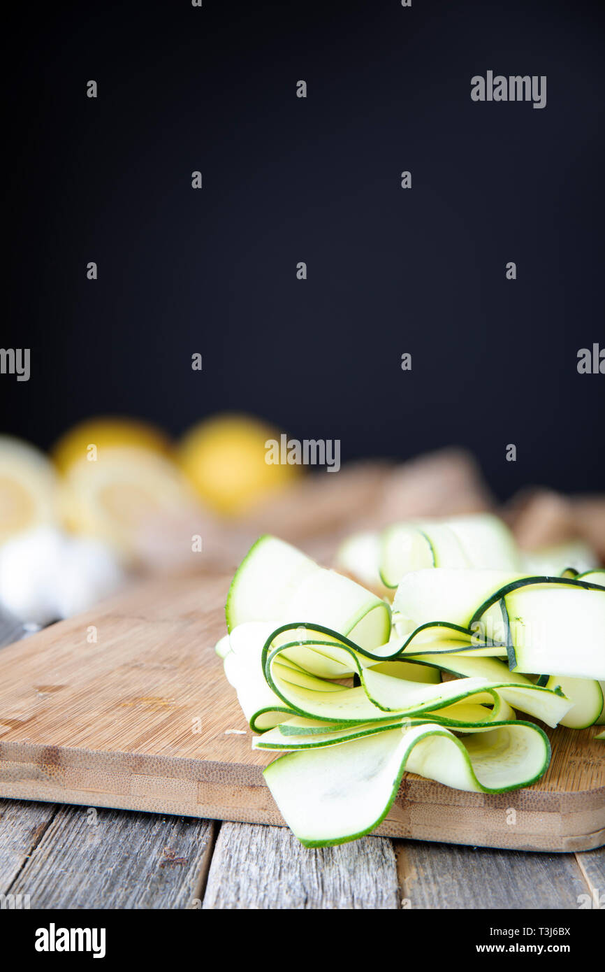 Frische Zucchini in Scheiben geschnitten in die Bänder und sitzen auf Holz Schneidebrett mit Kopie Platz oben. Stockfoto