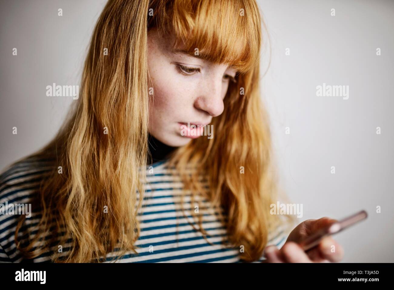 Mädchen, Teenager, Rothaarige, Blicke auf Ihr Smartphone Angst, studio Shot, Deutschland Stockfoto