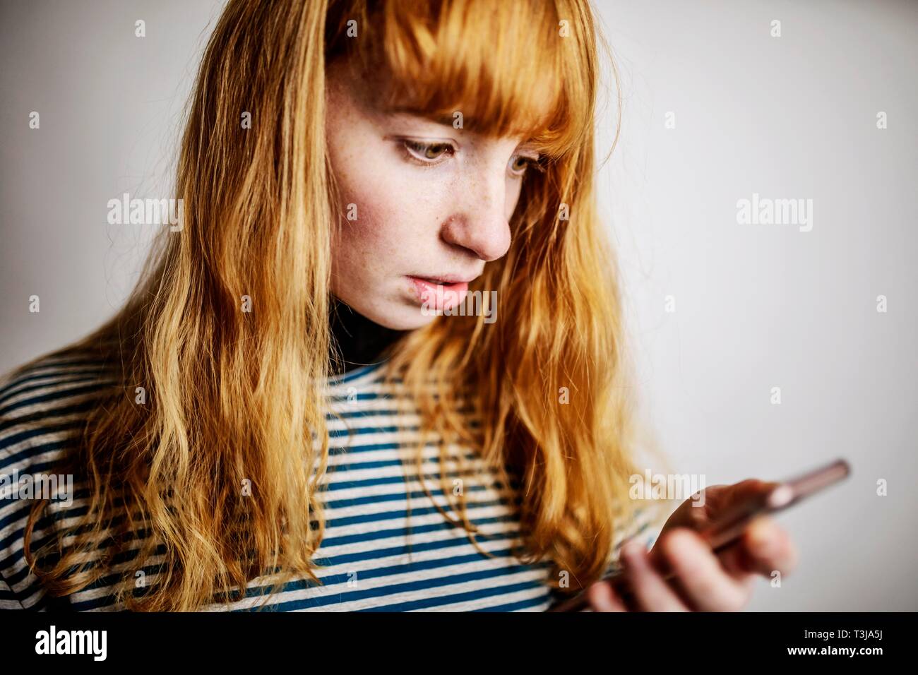 Mädchen, Teenager, Rothaarige, Blicke auf Ihr Smartphone Angst, studio Shot, Deutschland Stockfoto