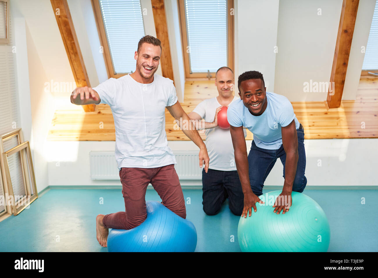 Drei Männer mit Gymnastikball gemeinsam Spaß haben in Fitness klasse und dumm um Stockfoto