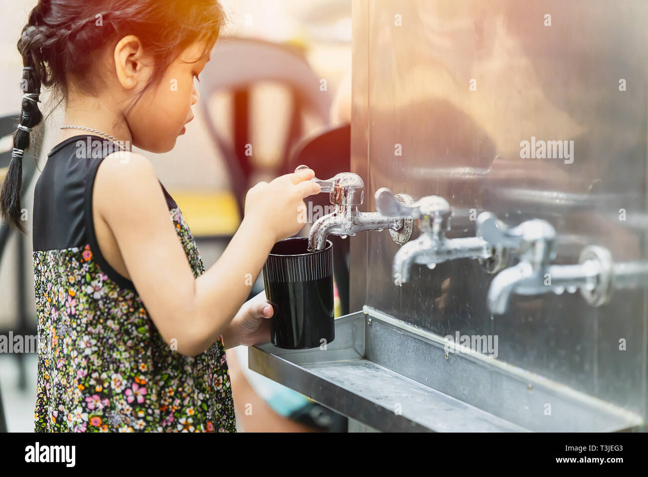 Kleines Mädchen Trinkwasser aus öffentlichen Kühltank Wasser gut tippen für gesunde und Aufenthalt in der Hitze Sommer hydratisiert, 21. Oktober 2018, Bangkok, Stockfoto