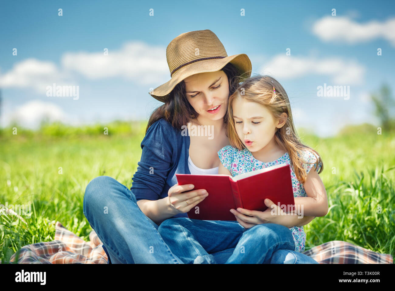 Mutter und Tochter lesen Buch über grüne Sommerwiese Stockfoto