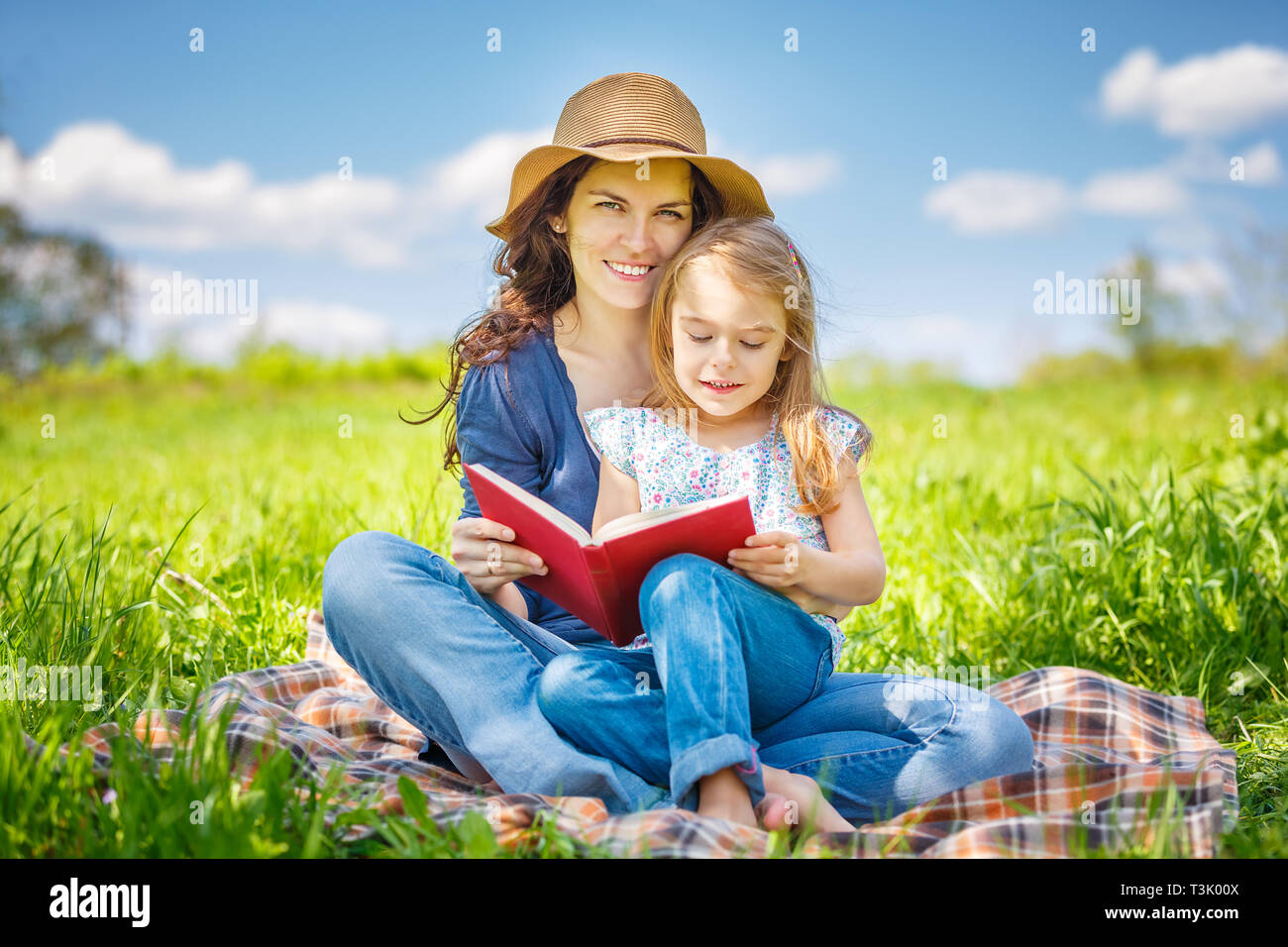 Mutter und Tochter lesen Buch über grüne Sommerwiese Stockfoto