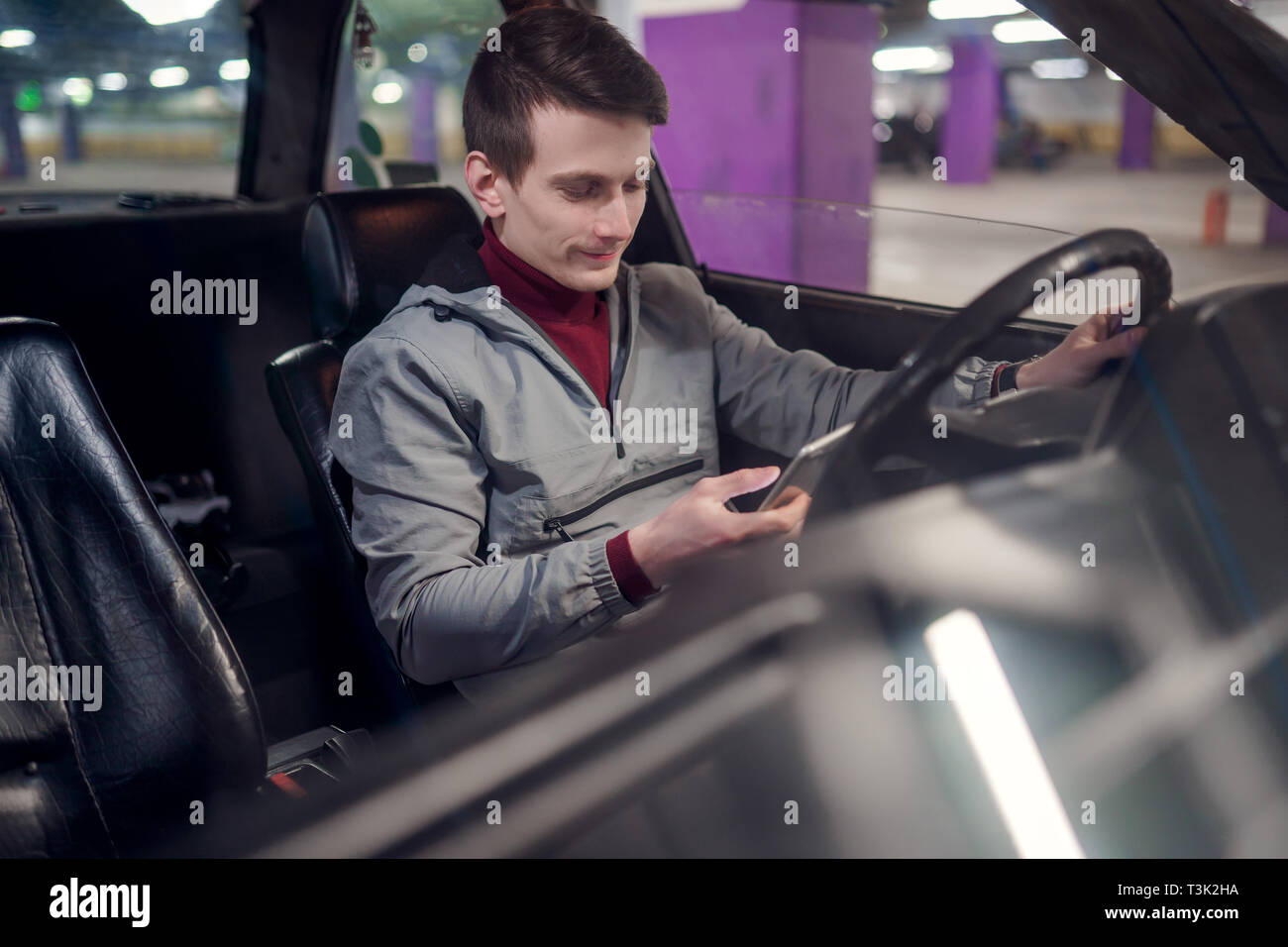 Foto von Seite der Junge männliche Fahrer mit im Freisprechmodus telefonieren im Auto sitzen auf u-Versicherung Stockfoto