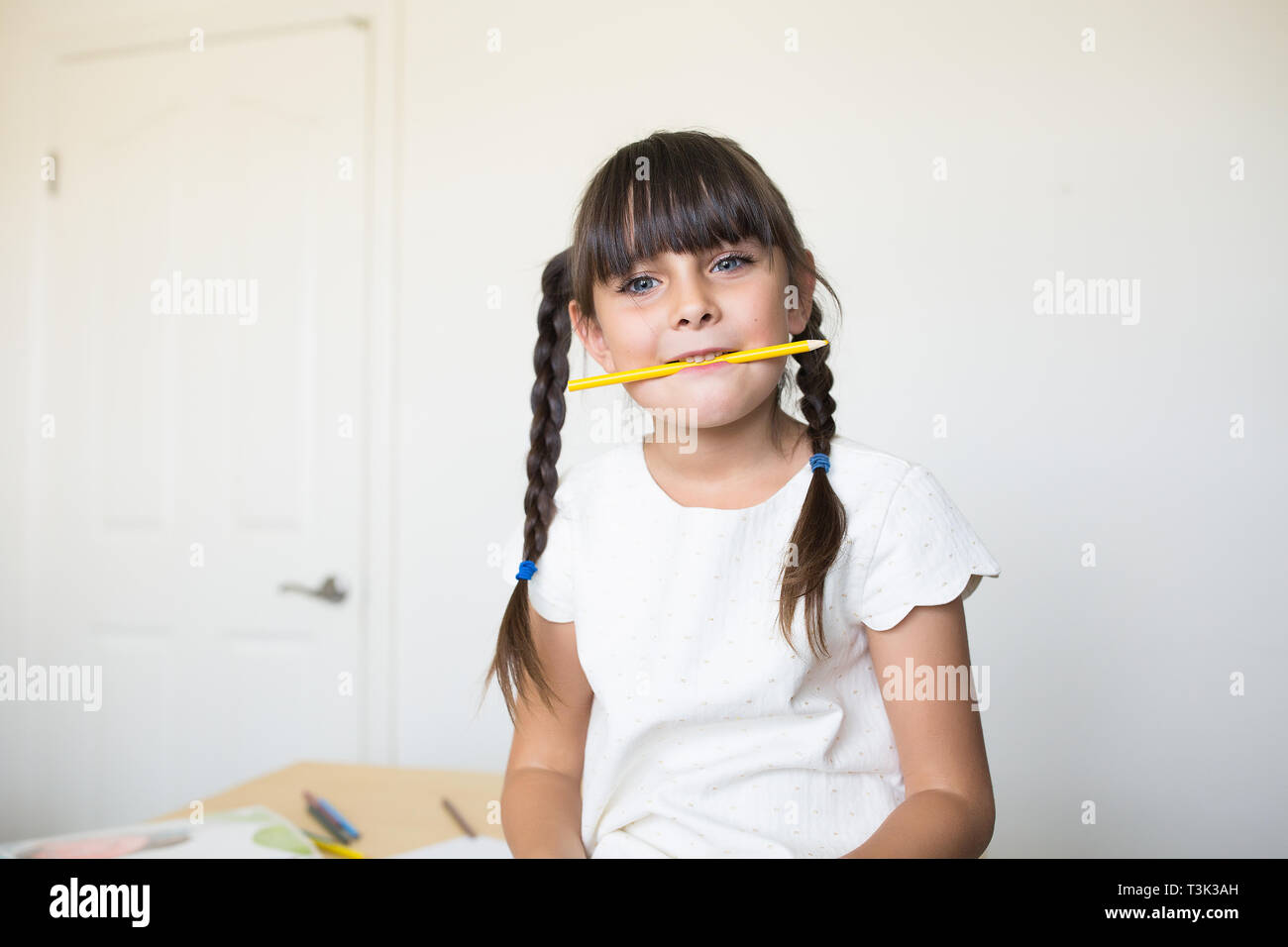 6-7 Jahre altes Mädchen hält einen Buntstift in Mund. Stockfoto