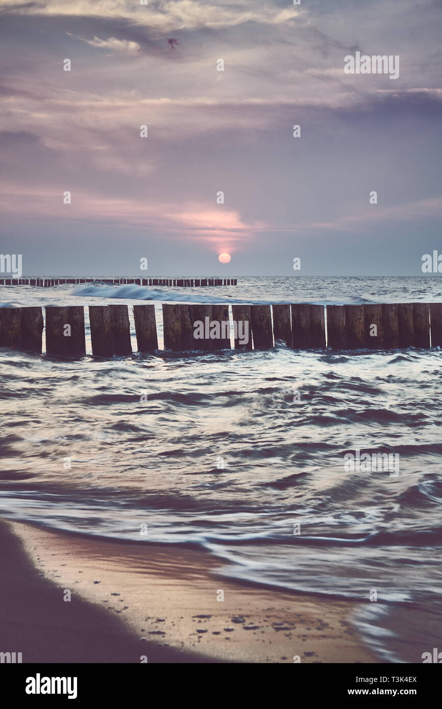 Holz- meer Wellenbrecher bei Sonnenuntergang, Farbe Tonen angewendet, Langzeitbelichtung mit Fokus auf Leiste. Stockfoto
