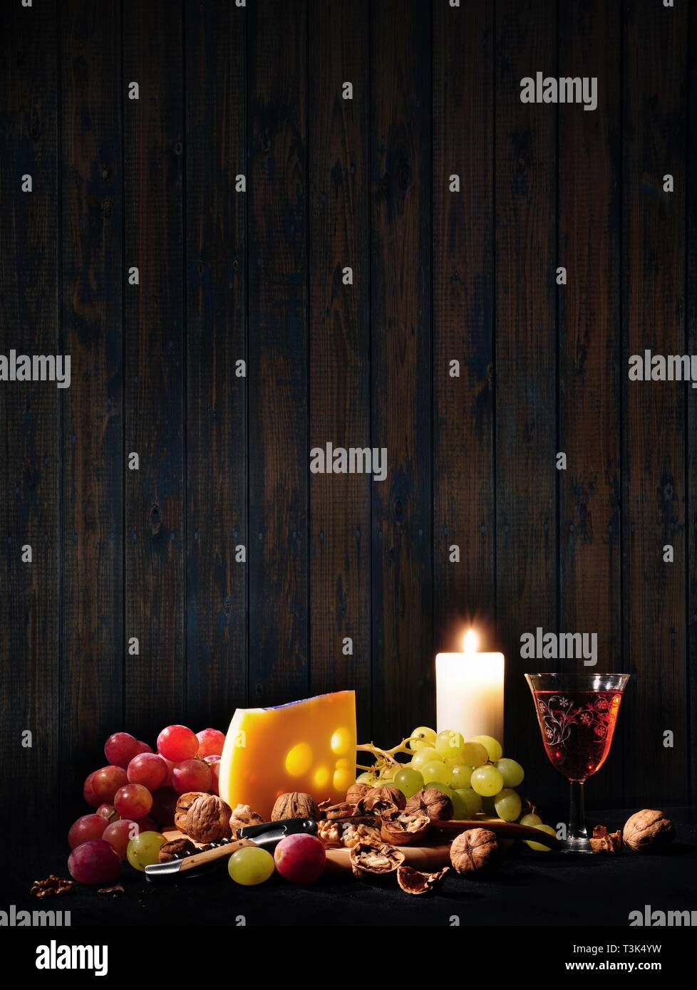 Stilleben mit Wein, Käse, Weintrauben und eine Kerze Stockfoto