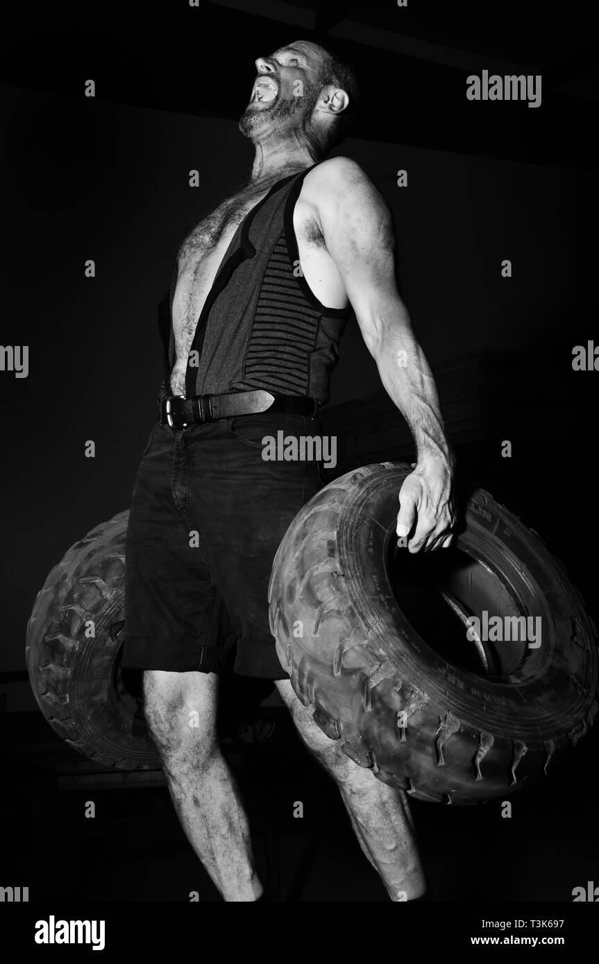 Mächtige Mann macht Bodybuilding mit alten Autoreifen Stockfoto