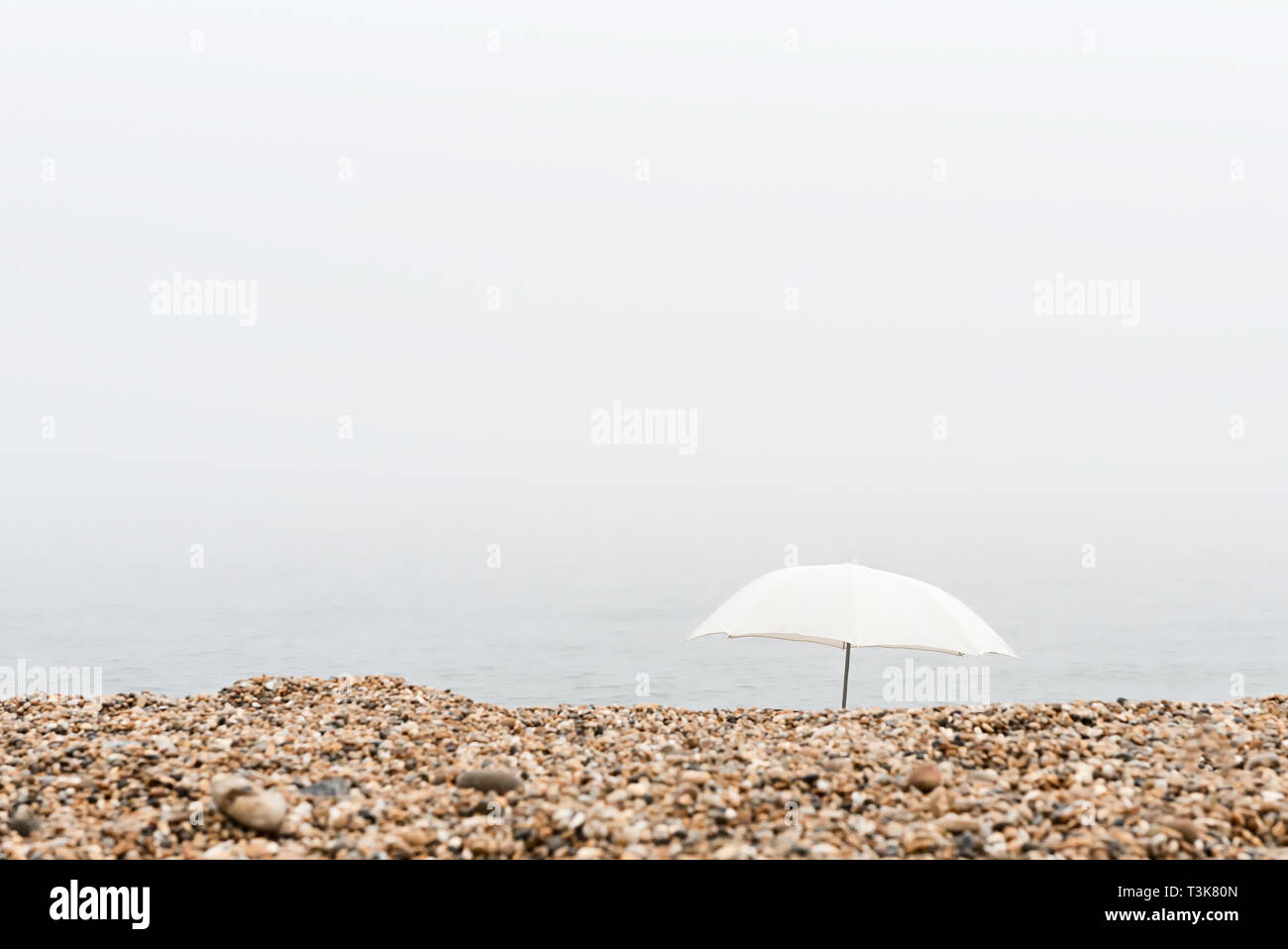 Sonnenschirm am Strand an einem nebligen Tag Stockfoto