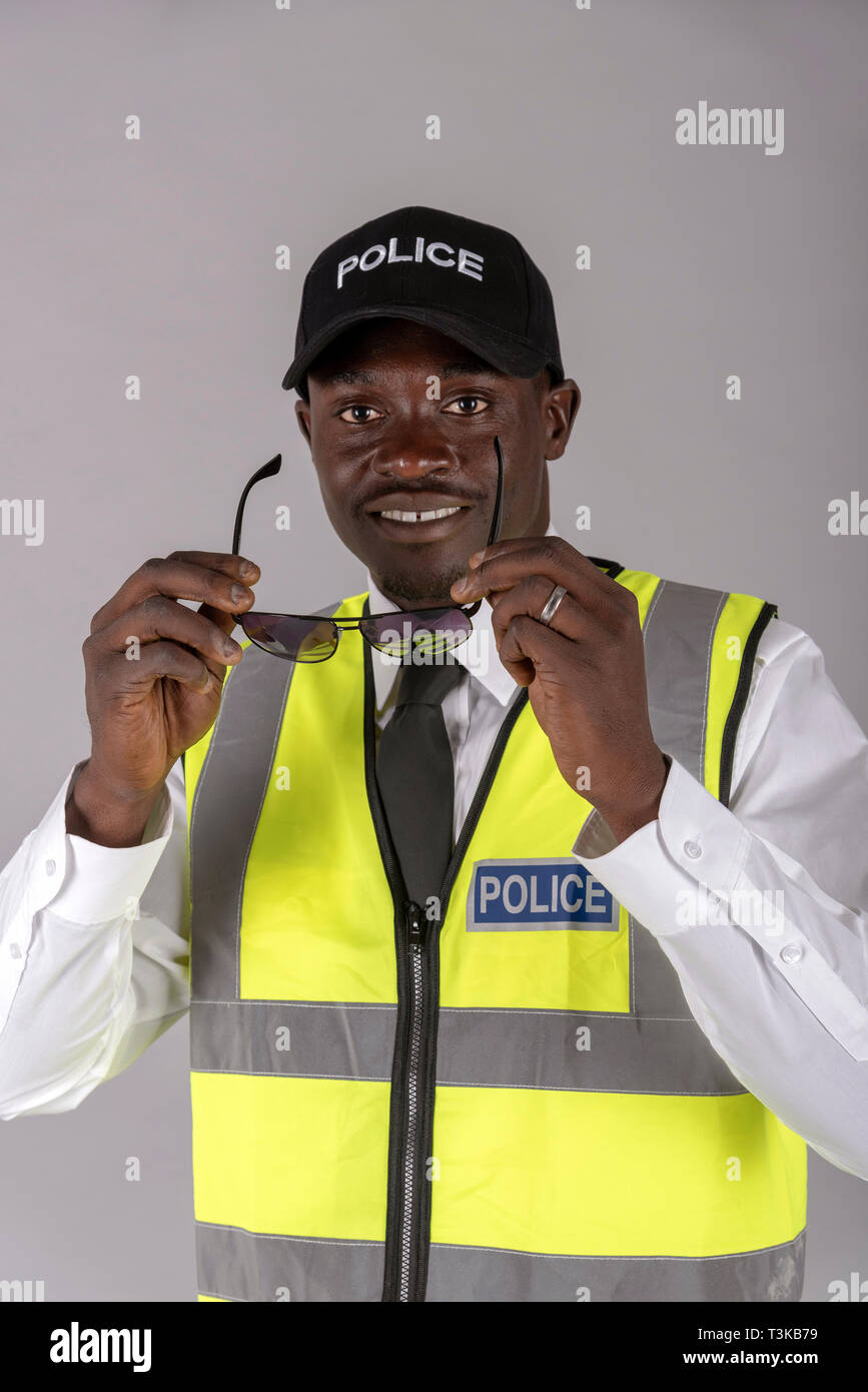 Porträt eines lächelnden Polizisten in Uniform und hält ein paar dunkle Brille zum Schutz der Augen. Stockfoto