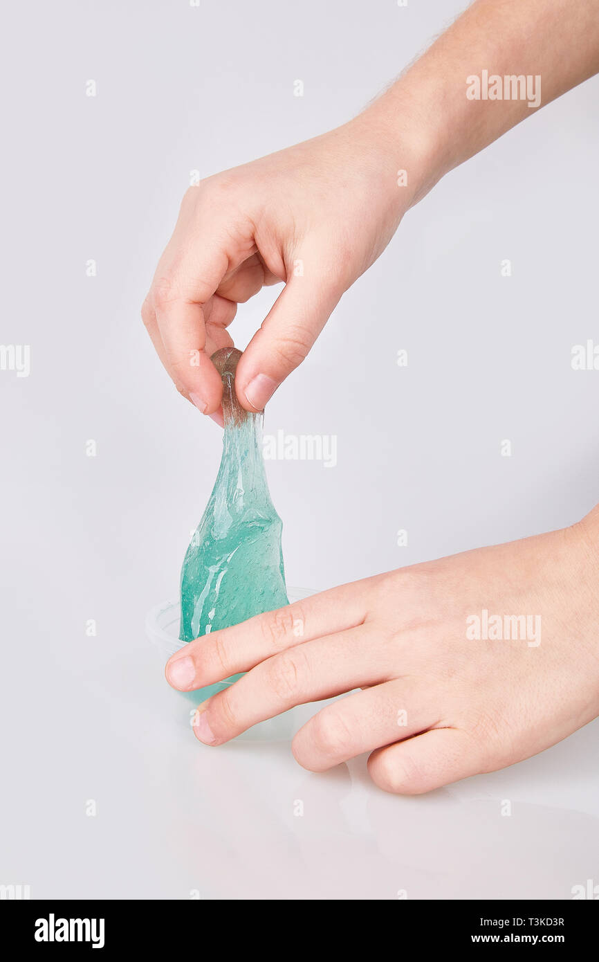 Kid's Hände halten ein transparent grün Schleim auf weißen isoliert. Moderne klebrige transparente Spielzeug Stockfoto