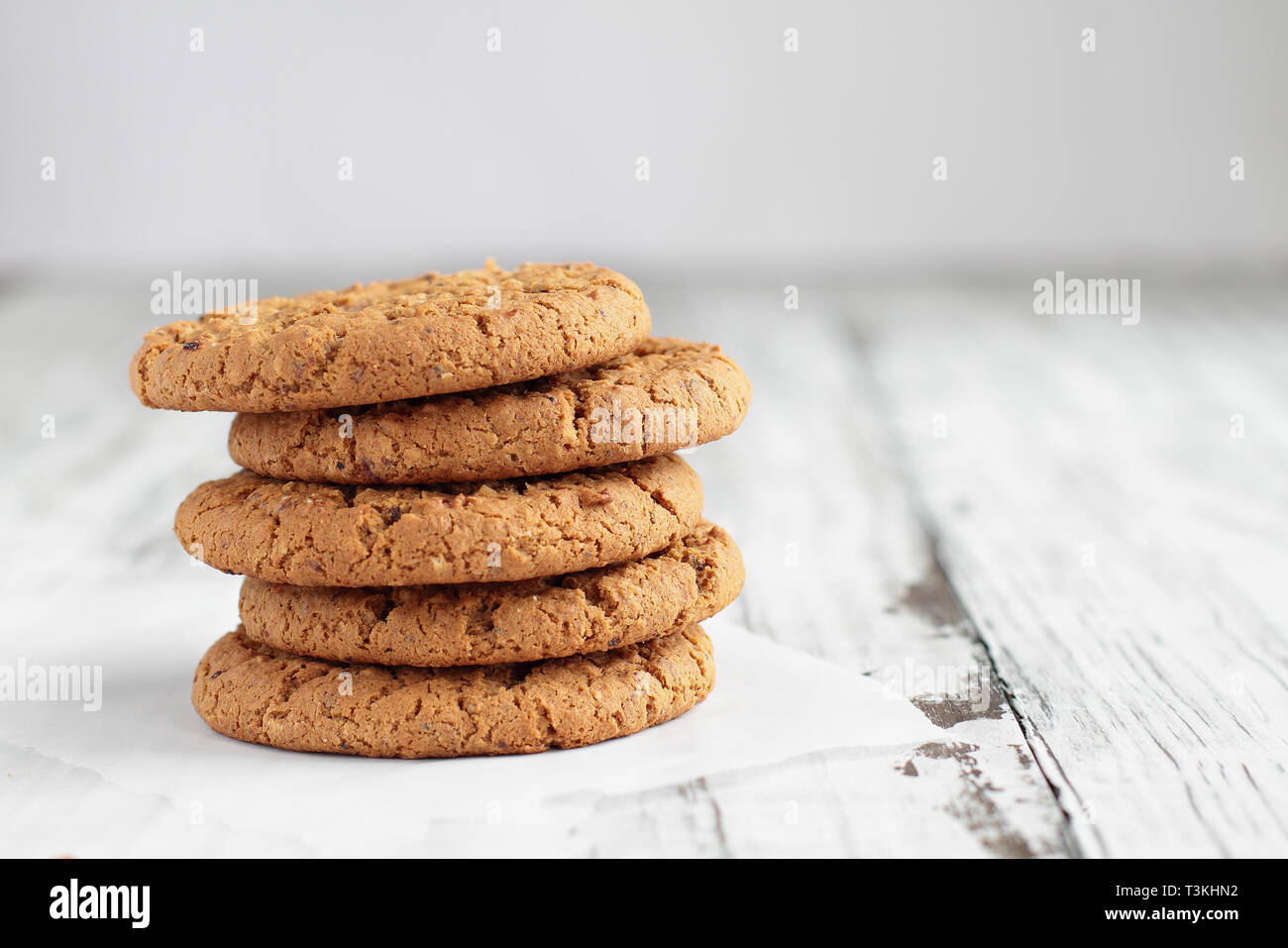 Stapel von frischen, hausgemachten Haferflocken Cookies mit einer Flasche Milch auf einem weißen Tisch vor einem weißen Hintergrund. Stockfoto