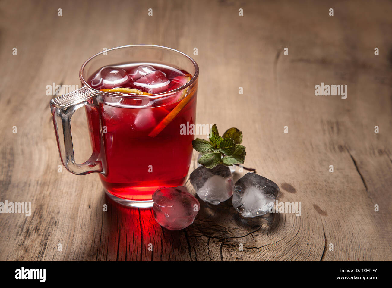 Sommer iced Drink - hibiskus kalten Tee mit Eis und Minze. Tasse Hibiscus kalten Tee mit Eis, Zitrone und Minze auf vintage Holz- Hintergrund Stockfoto
