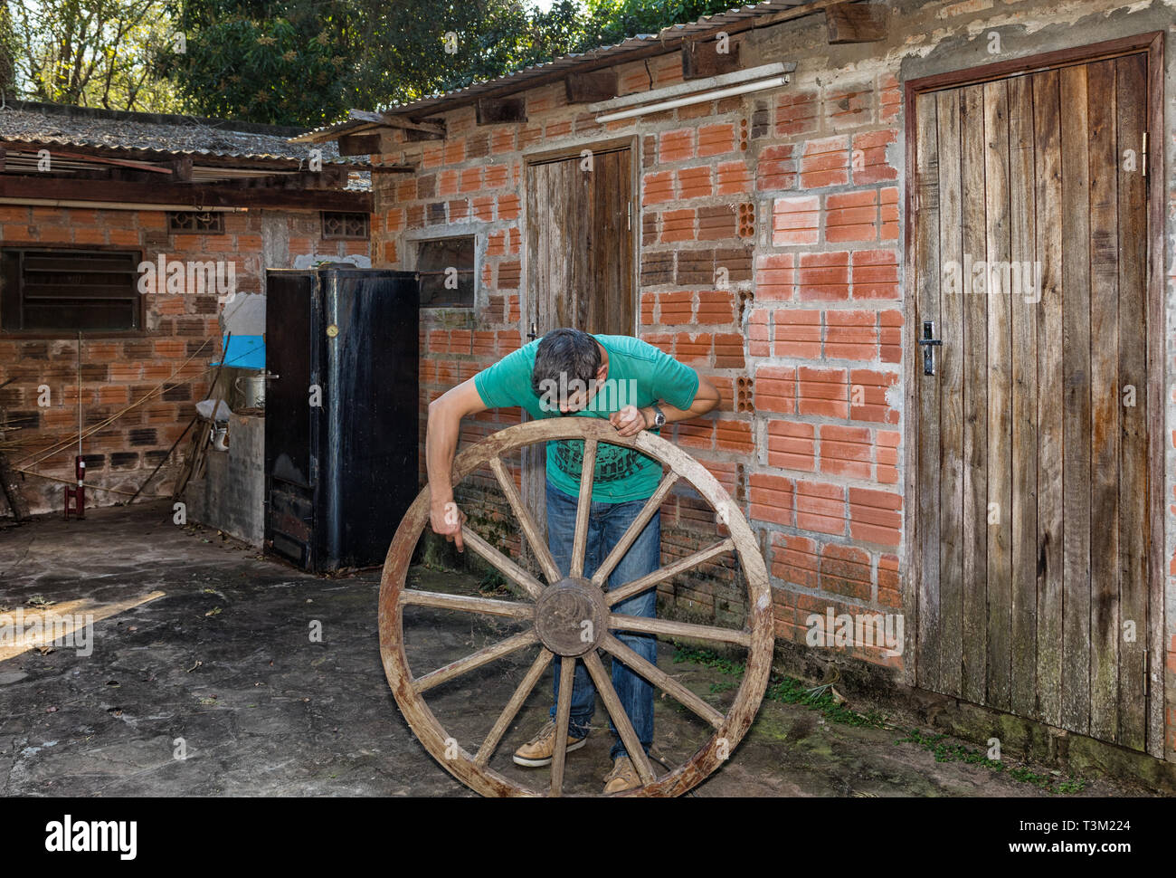 Ein Mann prüft ein altes hölzernes Rad. Stockfoto