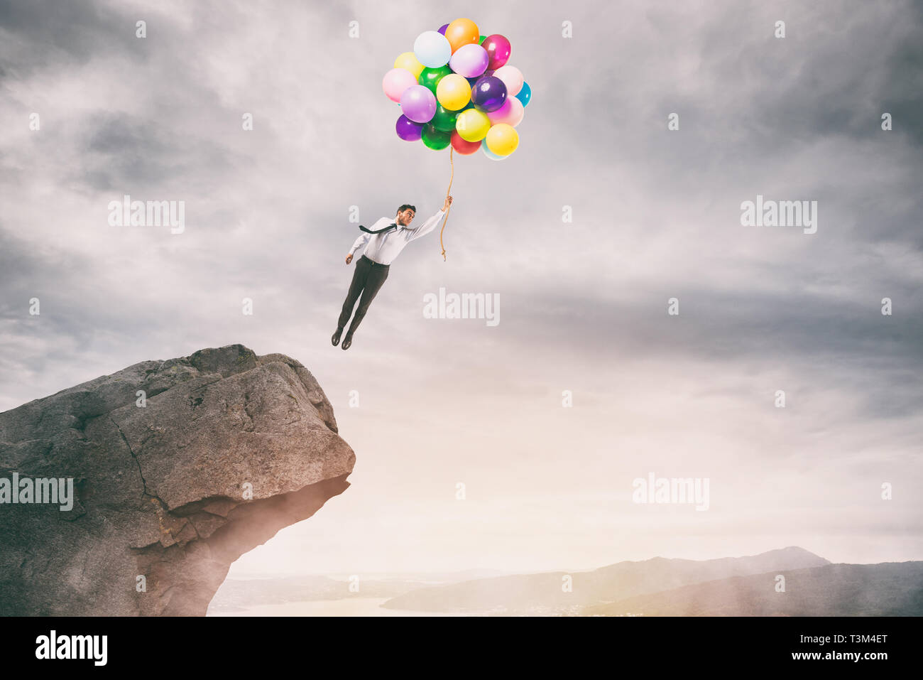 Kreative Unternehmer halten bunte Luftballons fliegt vom Gipfel eines Berges Stockfoto