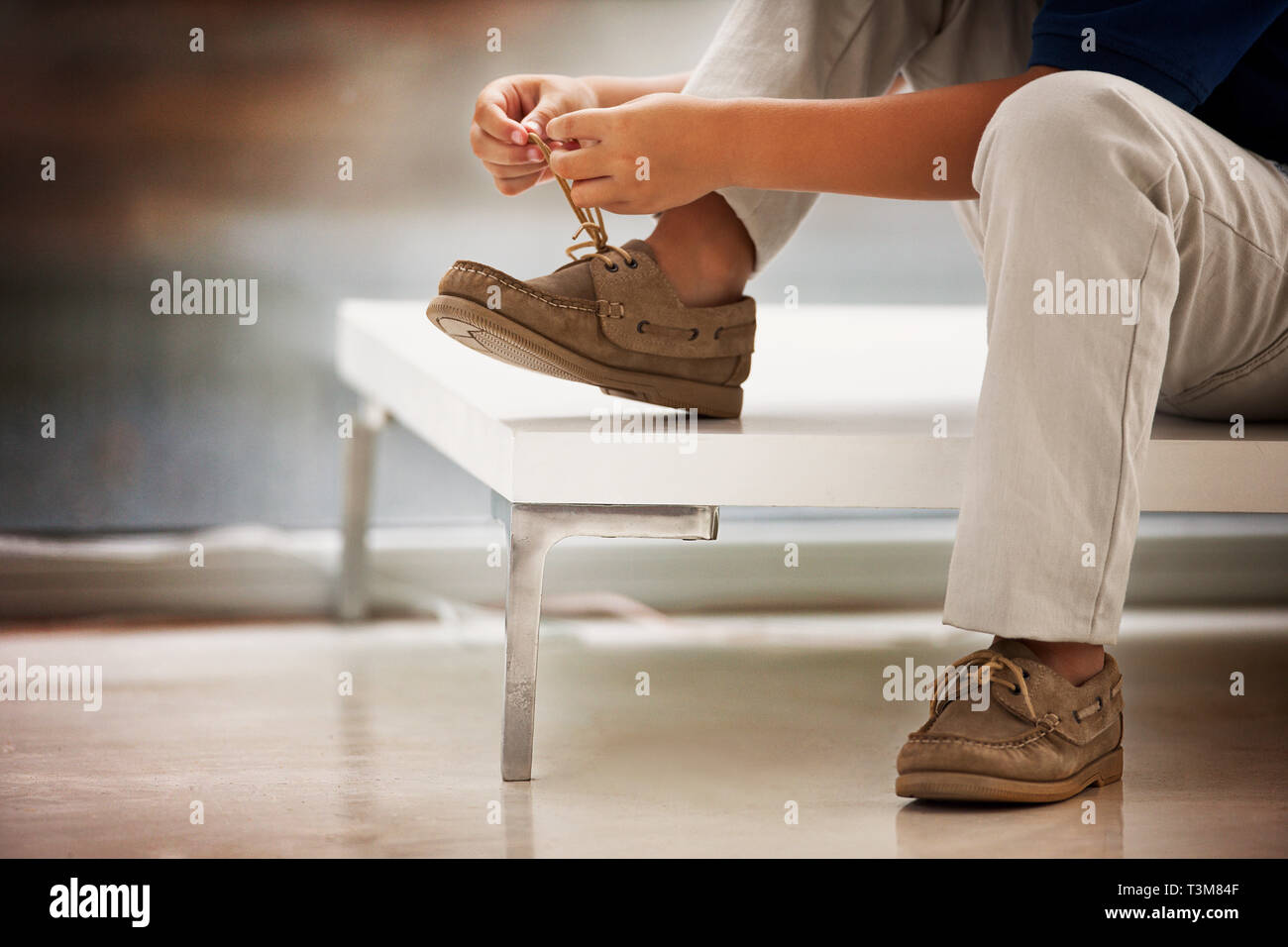 Junge tragen deck Schuhe bindet seine Schnürsenkel. Stockfoto