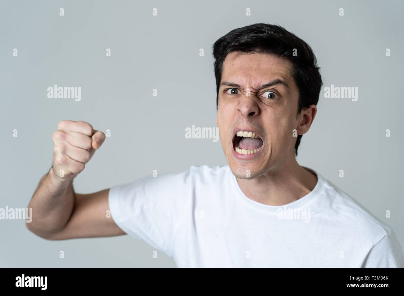 Der junge Kaukasier Männlich mit einem wütenden Gesicht. Suchen verrückt, Verrückter, aggressiver mit Faust geballt im Zorn. Auf weissem Hintergrund. Gesichtsbehandlung Stockfoto