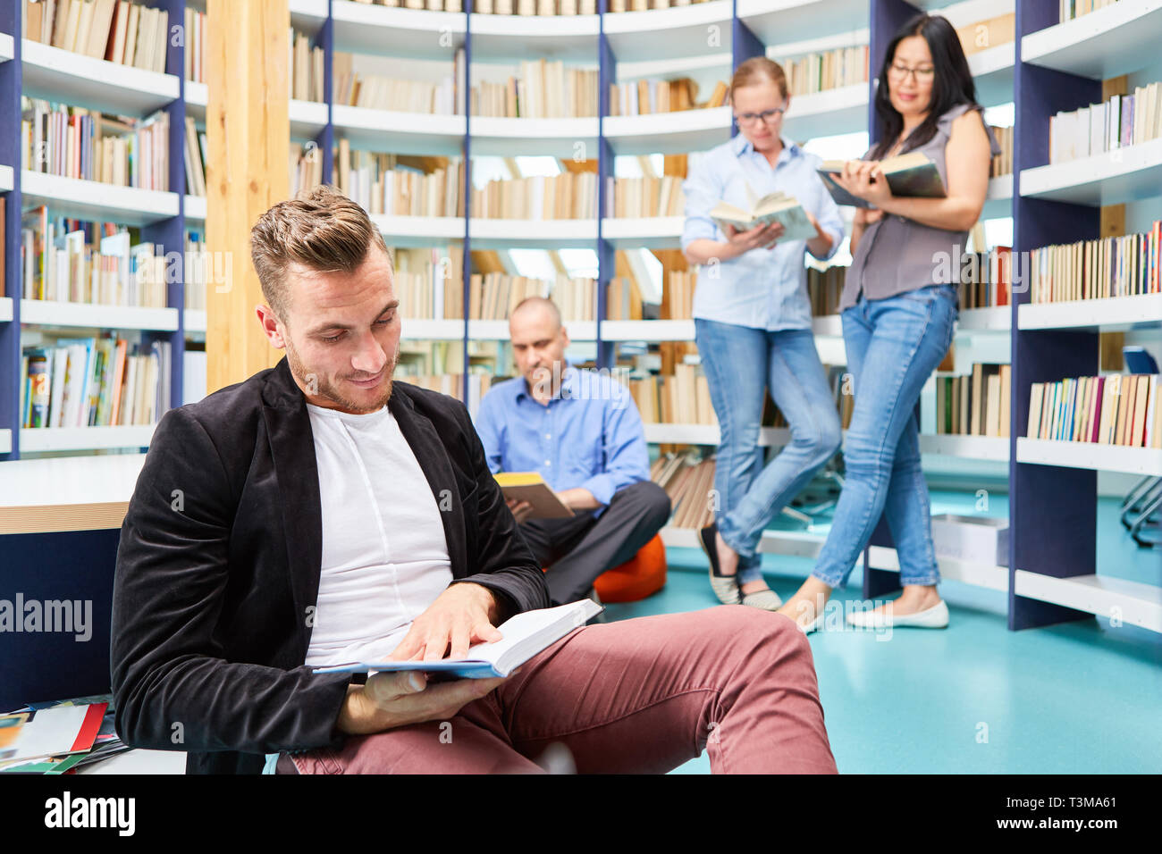 Gruppe von Jugendlichen beim zusammen Buch in der Bibliothek der Volkshochschule Stockfoto