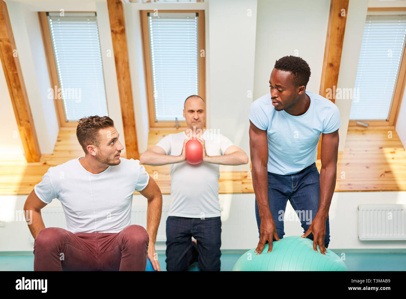 Gruppe der jungen Männer ist das Training mit Pilates gym ball in einer Klasse in der Turnhalle Stockfoto