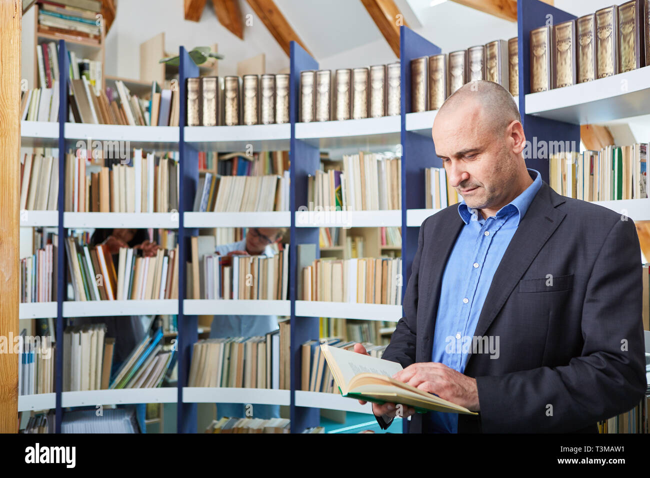 Der Mensch als Wissenschaftler oder Dozent liest in einem Buch in einer Bibliothek Stockfoto