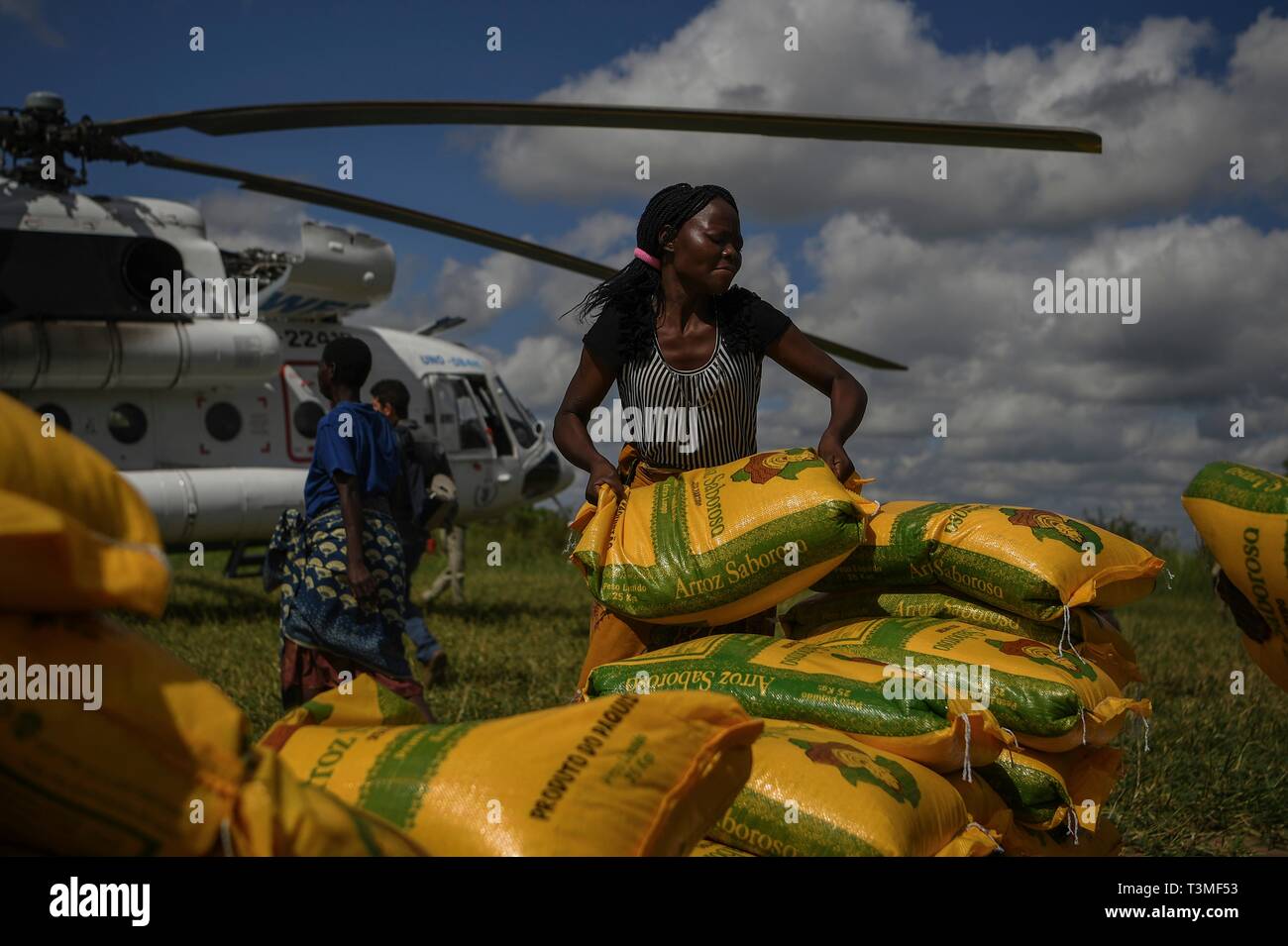 Freiwillige vor Ort helfen bei der Entladung die Nahrungsmittel aus einem Hubschrauber im Gefolge der massiven Cyclone Idai April 8, 2019 in der Nähe von Bebedo, Mosambik. Das World Food Programm, mit Hilfe von der US Air Force ist Transport der Hilfsgüter der verwüsteten Region zu unterstützen. Stockfoto