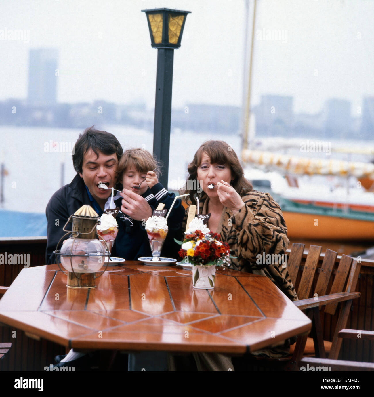 Deutscher Komponist, Sänger und Gitarrist Henner Hoier beim Eis essen mit Frau und Tochter an der Alster, Hamburg Deutschland Ca. 1980er. Deutsche Komponist, Sänger und Gitarrist Henner Hoier Eis essen mit Frau und Tochter an der Alster, Hamburg Deutschland Ca. 80er Jahre. Stockfoto