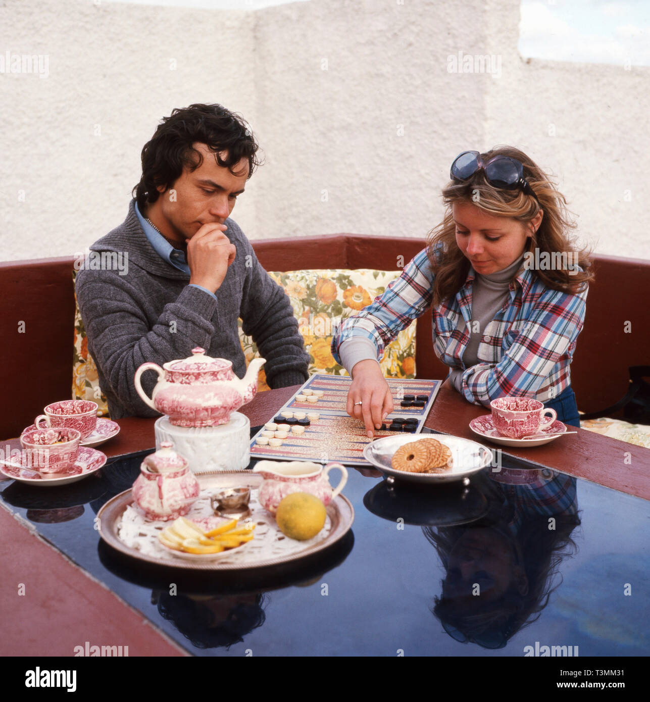Deutscher Komponist, Sänger und Gitarrist Henner Hoier mit Freundin beim Backgammon spielen im türkeirundreise, Ca. 1980er. Deutsche Komponist, Sänger und Gitarrist Henner Hoier Backgammon spielen mit einer freundin im sommer urlaub, Ca. 80er Jahre. Stockfoto