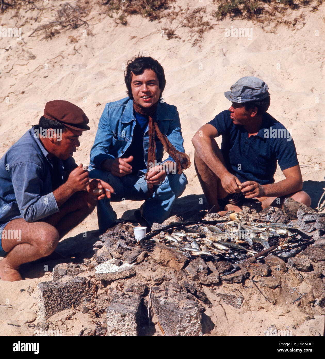 Deutscher Komponist, Sänger und Gitarrist Henner Hoier beim Grillen mit Einheimischen am Strand im türkeirundreise, Ca. 1980er. Deutsche Komponist, Sänger und Gitarrist Henner Hoier Grillen mit Einheimischen am Strand während der Sommerferien, Ca. 80er Jahre. Stockfoto