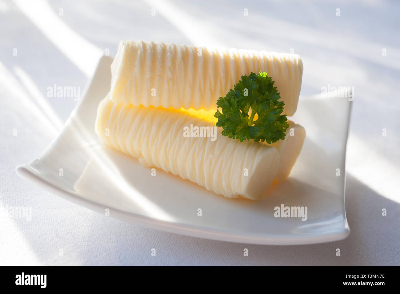 Butter Rollen mit Petersilie garnieren auf der sonnenbeschienenen Tisch Stockfoto