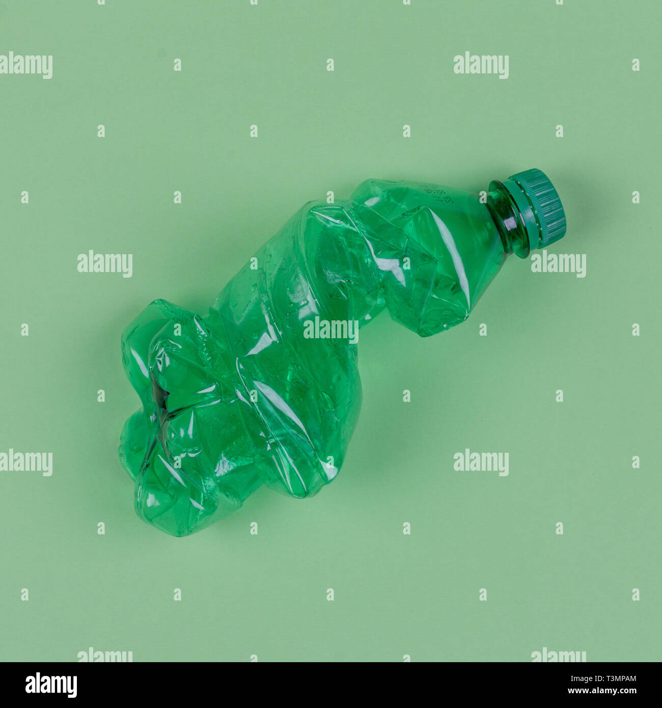 Eine grüne Flasche auf einem hellgrünen Hintergrund, Ansicht von oben. Das Konzept der das Problem der Verwendung von Plastiktüten und -behälter und Umwelt zu verbieten. Stockfoto