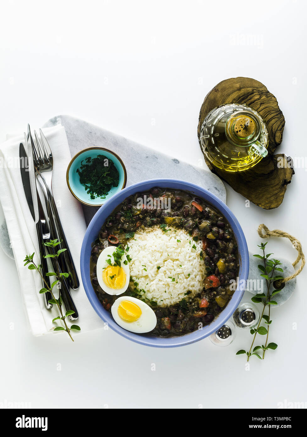 Reis mit schwarzen Bohnen und gekochtes Ei auf den Tisch mit Gewürzen und Olivenöl. Gesunde karibisches Essen Stockfoto