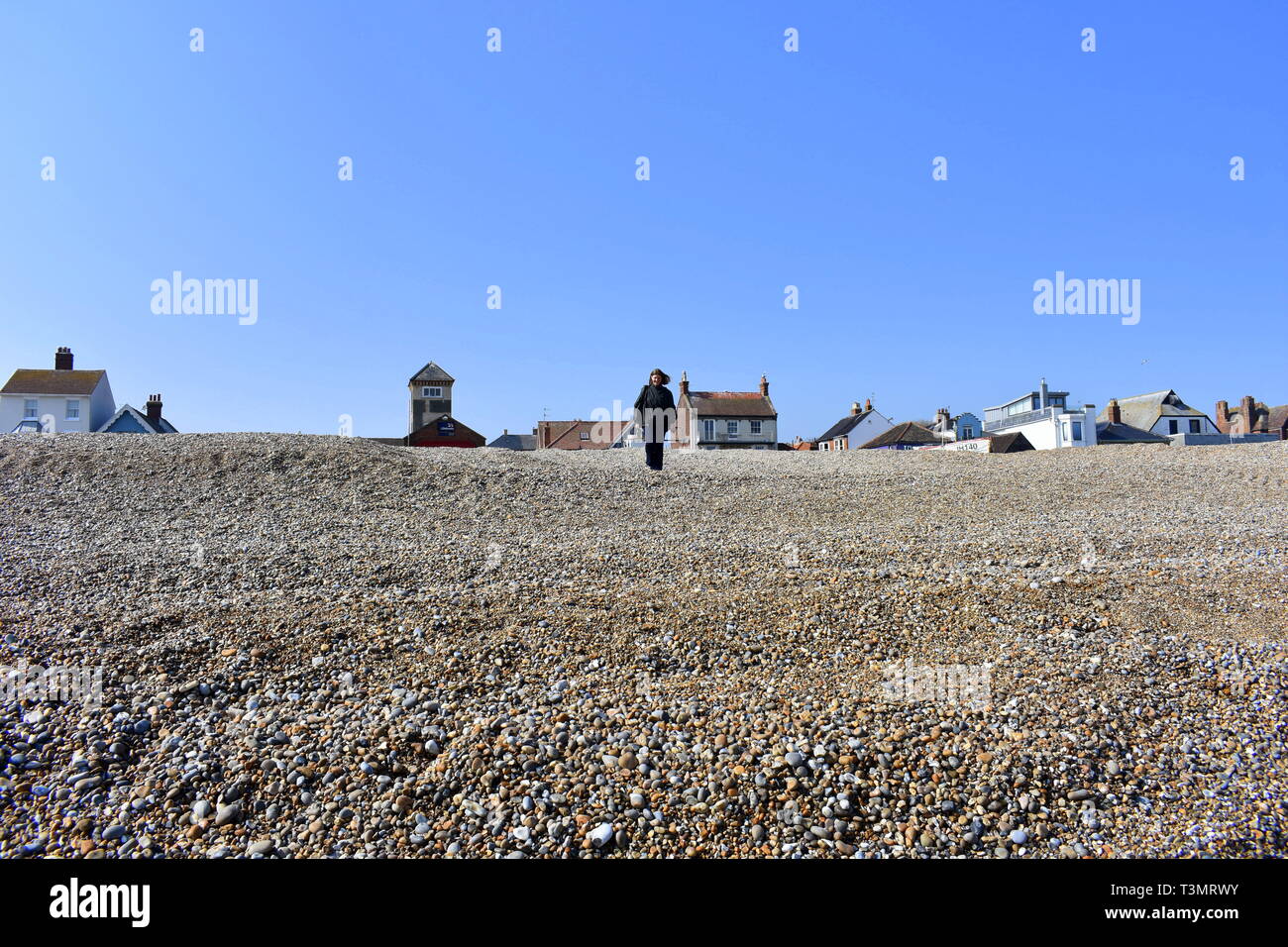 Sie suchen den steilen Kiesstrand in Richtung einer Dame nach unten wandern, Aldeburgh, Suffolk, England Stockfoto