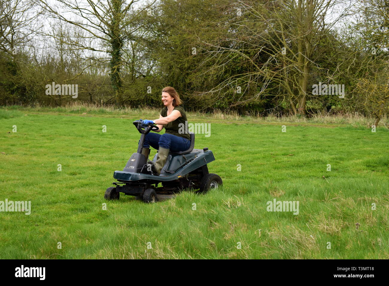 Frau schneiden das Gras auf einer auf Rasenmäher, Suffolk, England Stockfoto