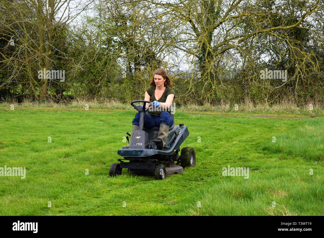 Frau schneiden das Gras auf einer auf Rasenmäher, Suffolk, England Stockfoto
