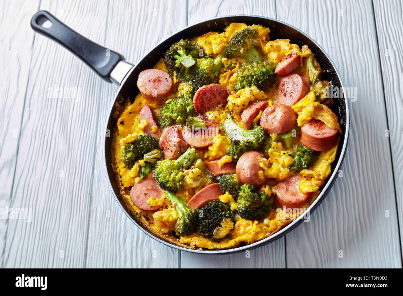 Leckere heiße Omelette mit Brokkoli und Würste in einer Pfanne bestreut mit frisch gemahlenem Pfeffer, horizontale Ansicht von oben, close-up Stockfoto