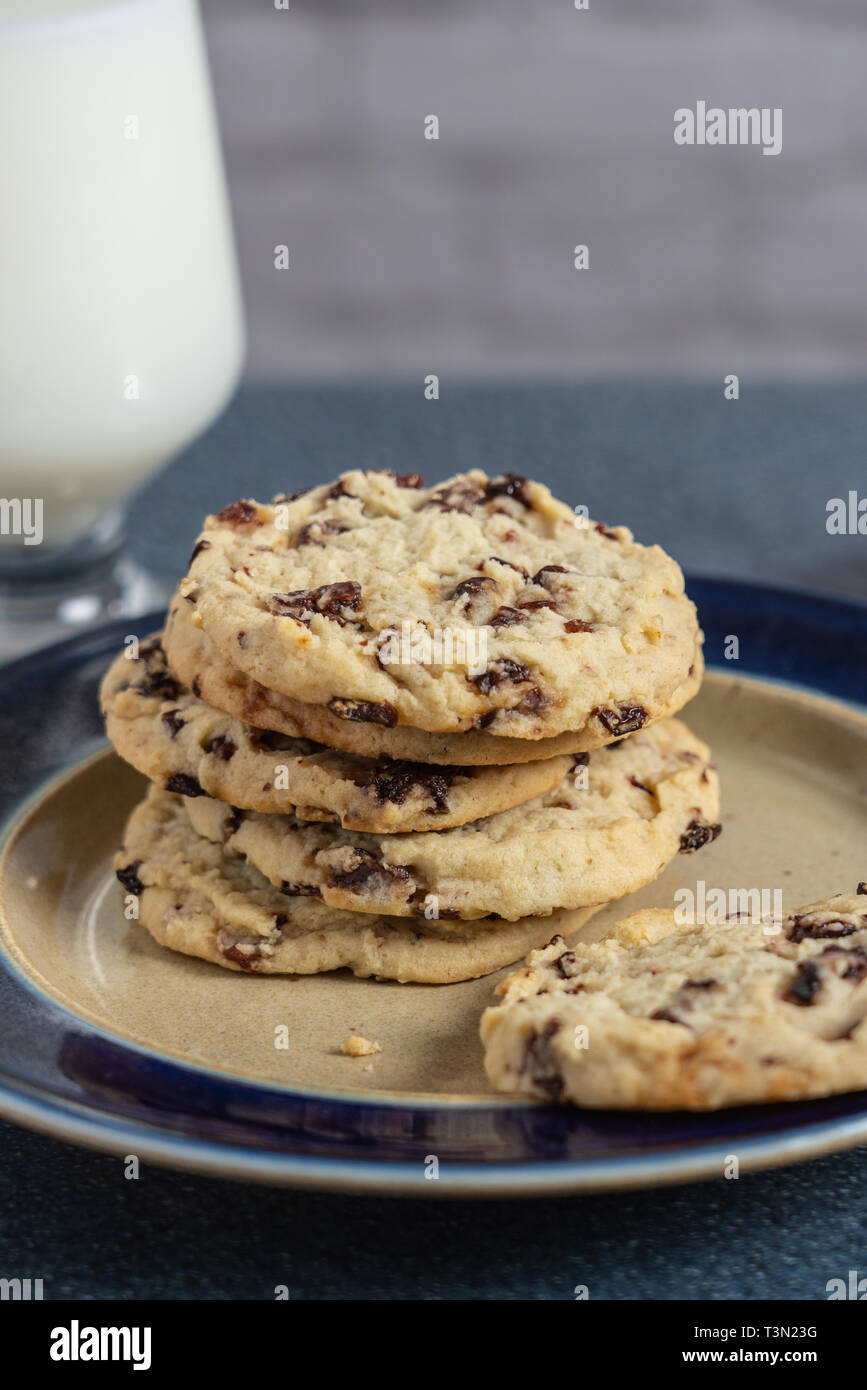 Gesunde Festlichkeit von getrockneten cherry Cookies auf einer Platte mit einem Glas Milch sitzen auf einem blauen Arbeitsplatte. Kirschen sind Antioxidantien und sind Anti-Inflammat Stockfoto