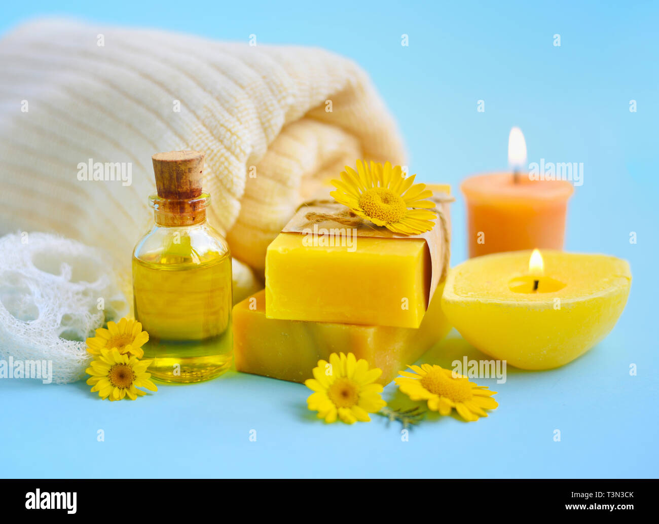 Spa Komposition mit natürlicher Seife, Kerzen, Aroma Öl in Flaschen und  Blüten auf blauem Hintergrund Stockfotografie - Alamy