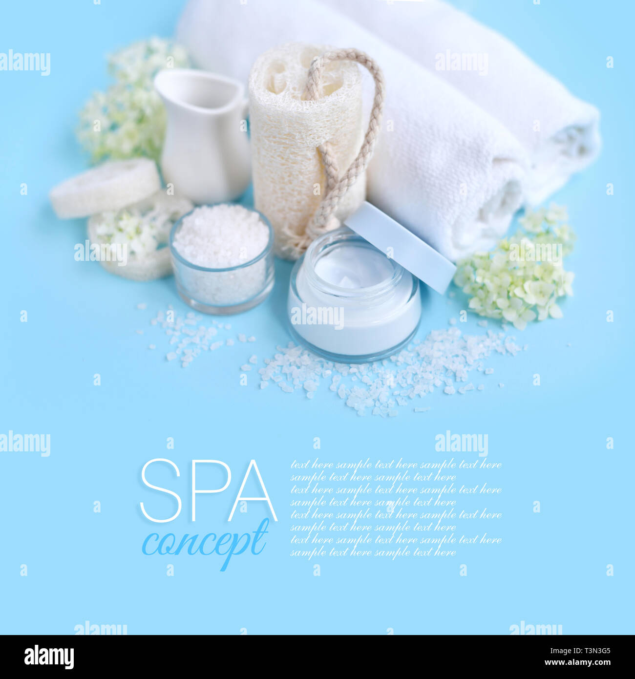 Spa Zusammensetzung mit Sahne, Salz, Handtuch und Blumen auf einem blauen Hintergrund. Stockfoto