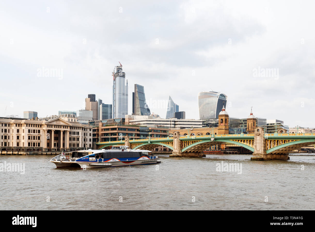 Die Southwark Bridge und die Innenstadt von London über die Themse von Bankside, London, Großbritannien, eine Thames Clipper River Boat im Vordergrund,, April 2019. Stockfoto