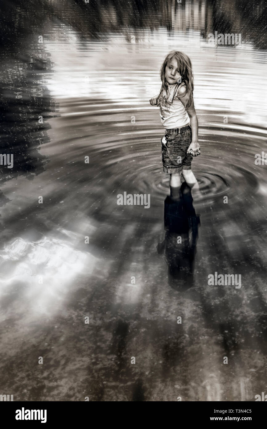 Getonten Bild eines 7-jährigen Mädchens Paddeln in einem Teich an einem Sommertag, über die Schulter schauen Stockfoto