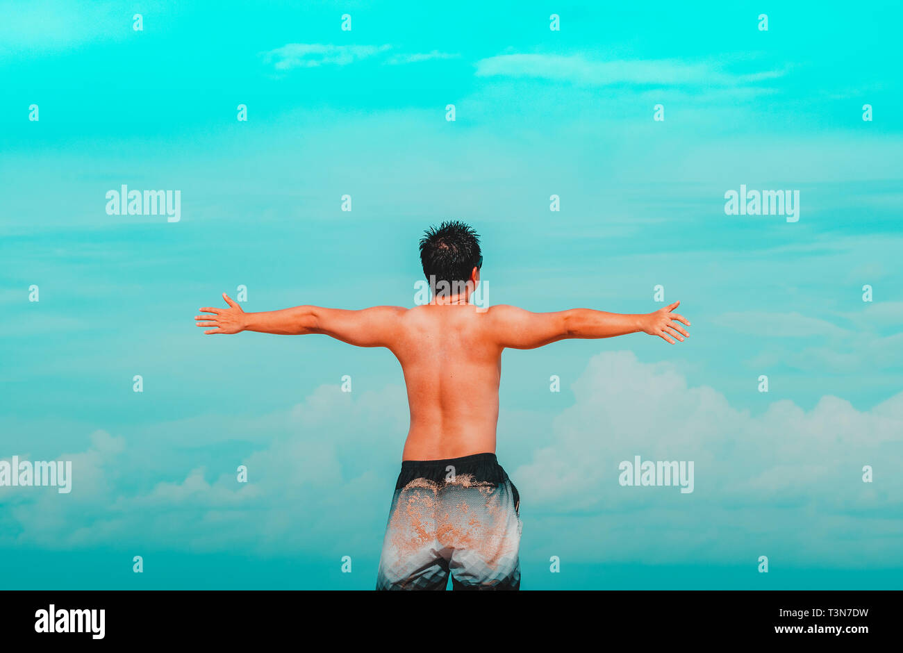 Mann ohne Hemd, mit offenen Armen in den Himmel, Freiheit Gefühle. Cyan und orange Tönen. Stockfoto