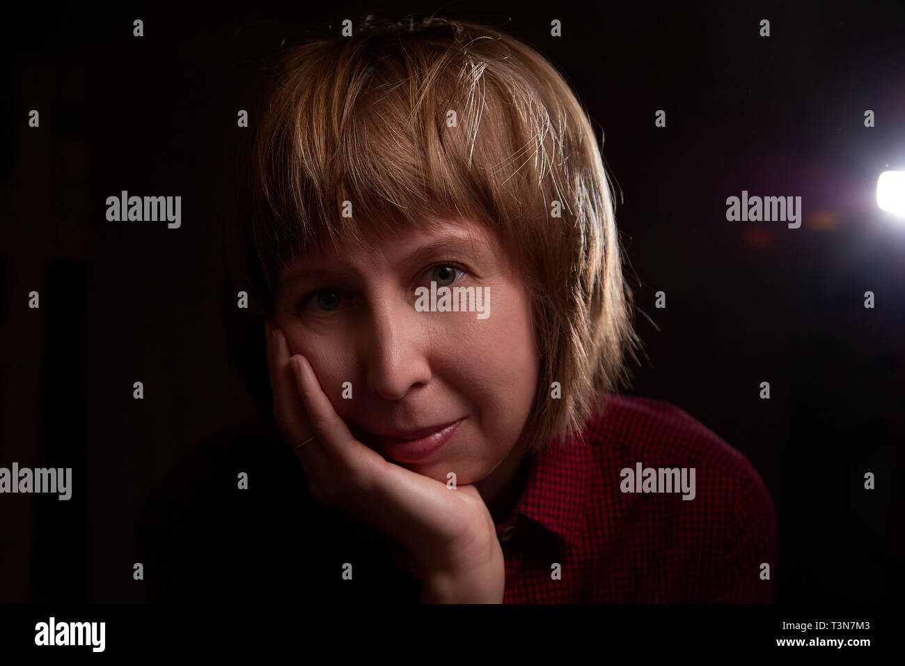 Portrait von hässlich, aber süßes Mädchen mit dicken Backen und dunklen Hintergrund. Fotoshooting von Frauen mittleren Alters im Studio mit interessanten Hintergrundbeleuchtung Stockfoto