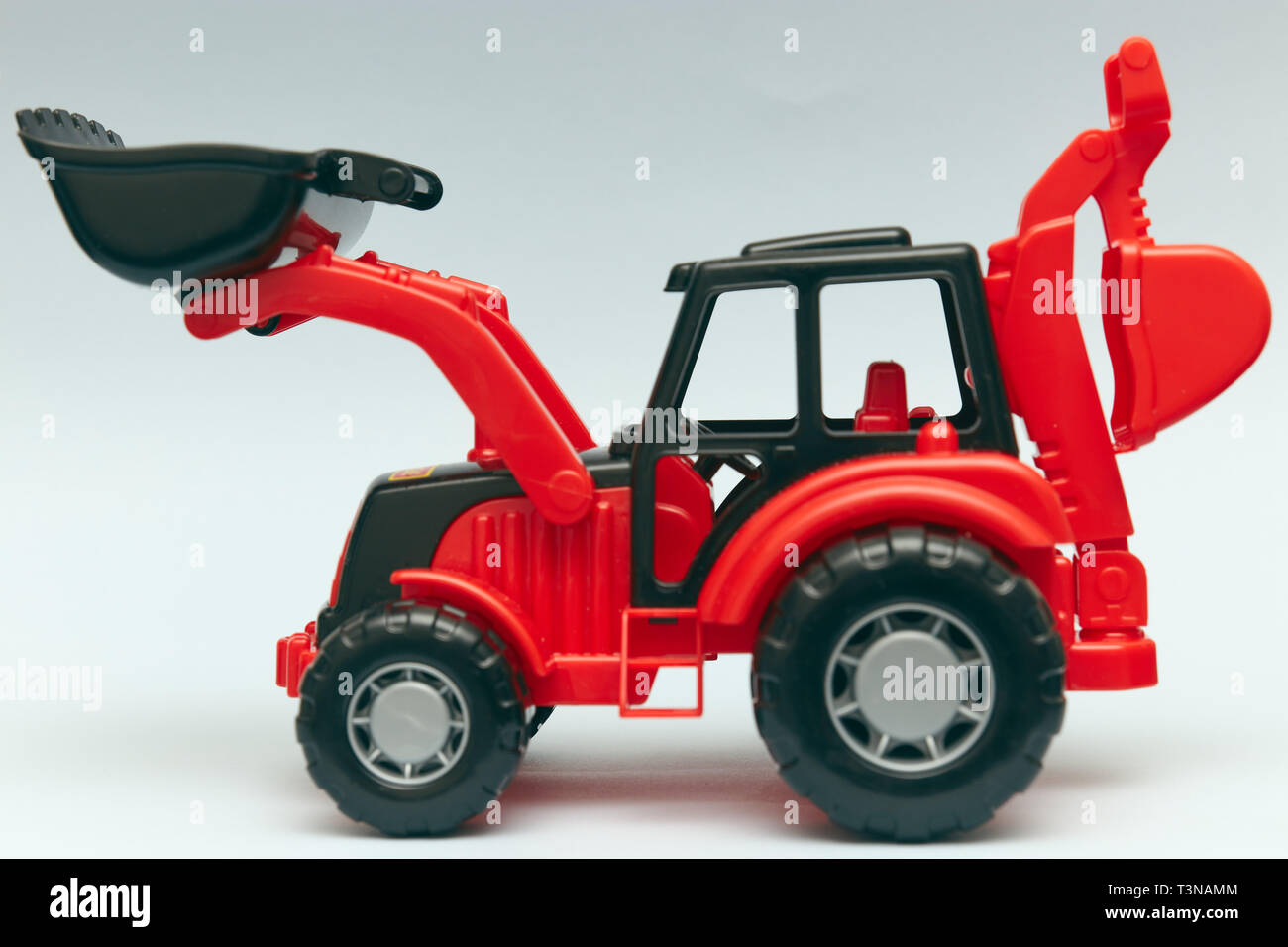 Spielzeug roten Traktor auf einem hellen Hintergrund. Close-up, Kinder Birne industrielle Auto, Kunststoff Stockfoto