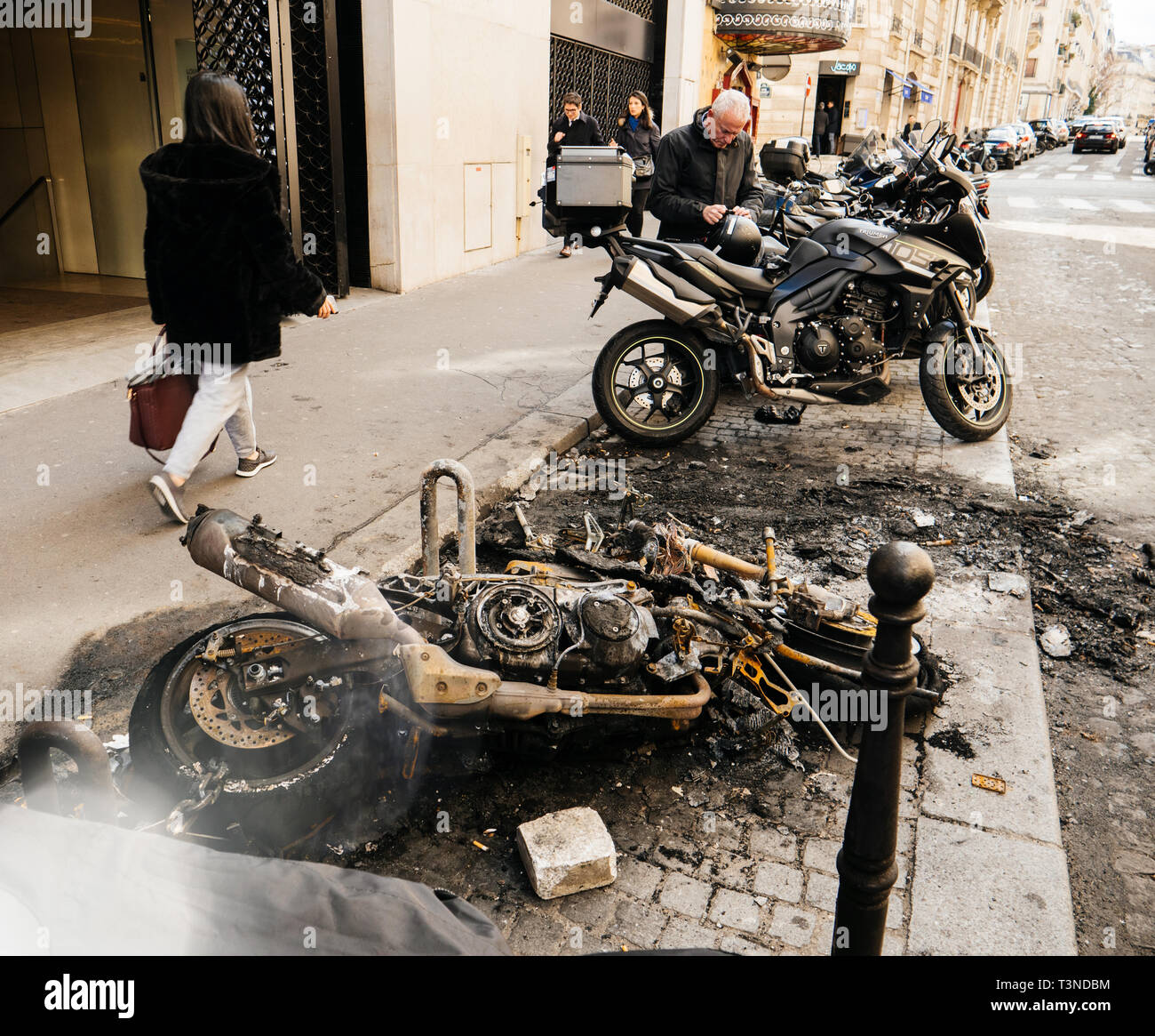 Paris, Frankreich, ca. 2019: Fußgänger zu Fuß in der Nähe verbrannt Luxus  sport Motorräder vor Maison Louis Vuitton 60, Rue de Bassano ein paar Meter  Champs Elysees Avenue Protest von gelben Westen