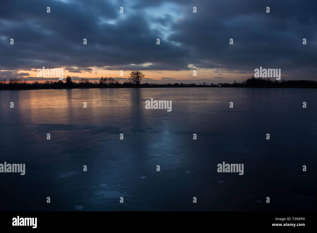 Bewölkter Himmel nach Sonnenuntergang auf dem zugefrorenen See und reflektieren Licht auf der Ice-Abend winter Blick Stockfoto